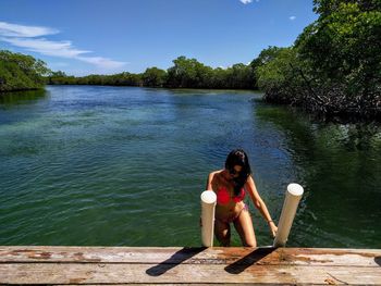 Woman coming out from lake against trees