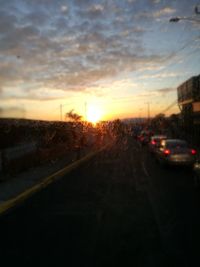 Cars on road against sky during sunset