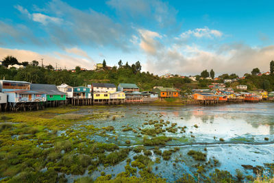 Houses by lake against sky