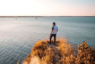 Rear view of man looking at sea against sky