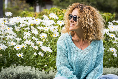 Young woman wearing sunglasses while standing against plants