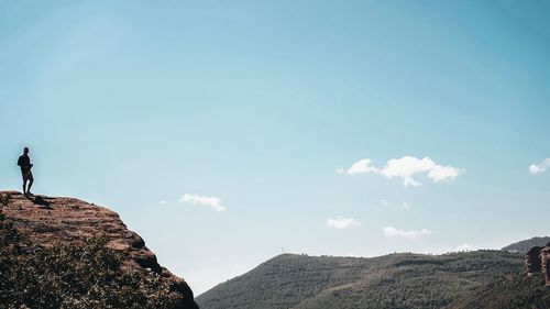 Man standing on rock against sky