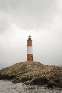 Lighthouse by sea against sky