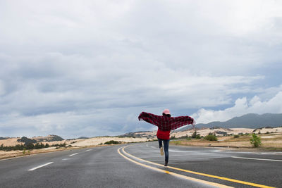 Rear view of woman walking on road against sky