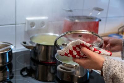 Woman cooking on cooker in the kitchen with hot steam and pots on a ceran stove to cook