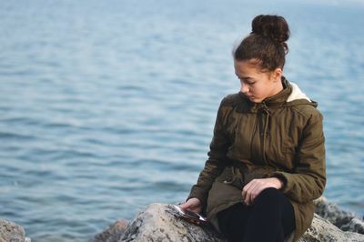 Woman sitting on rock by sea