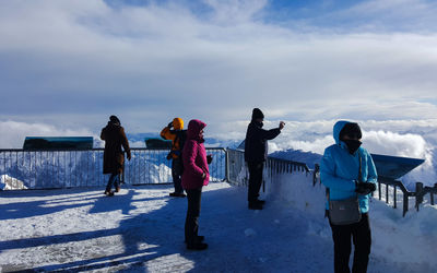 People standing on snow covered landscape against sky