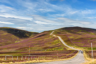 Scenic view of road by mountain against sky