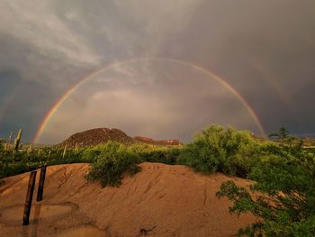 Scenic view of rainbow over field against sky