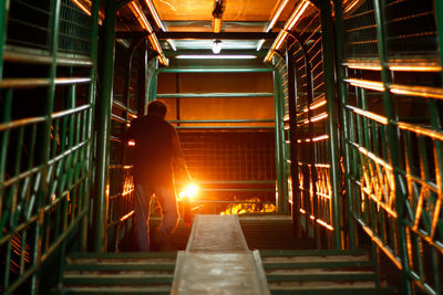 Rear view of man walking on staircase in building