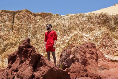 Man standing on rock formation during sunny day