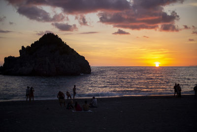 Silhouette people on beach against sky during sunset