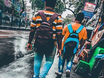 Rear view of people walking on road in city