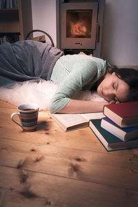 High angle view of woman with books sleeping on hardwood floor at home