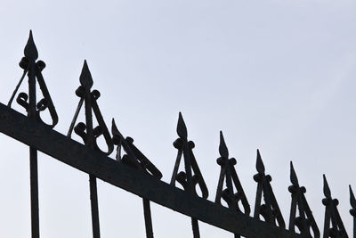 Low angle view of metal gate against clear sky
