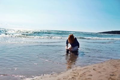 Rear view of woman on beach against sky