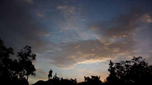 Silhouette of trees against cloudy sky