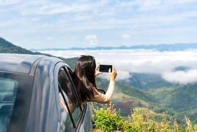 Side view of woman photographing through binoculars