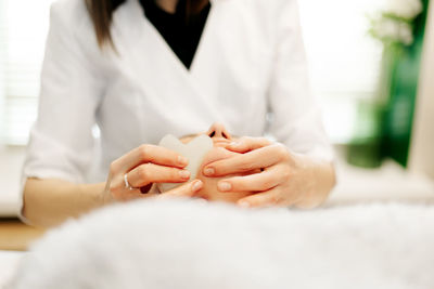 Neat female hands of a massage therapist-cosmetologist do massage with a gouache scraper 