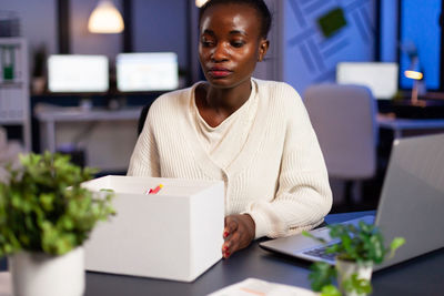 Young woman using mobile phone while sitting on table