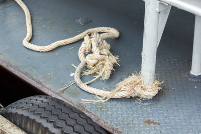 High angle view of rope tied to metal on footpath