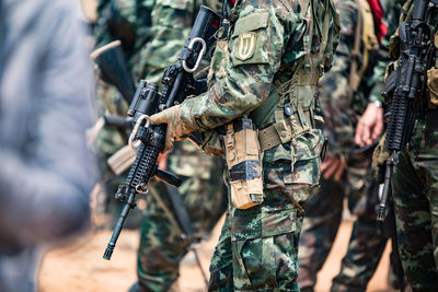 Midsection of army soldiers with rifle