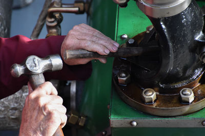 Cropped hands of person holding hand tools on equipment