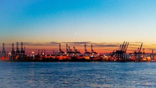 Commercial dock by sea against sky during sunset