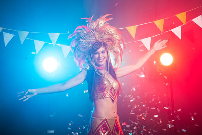 Woman standing by illuminated lighting equipment at night