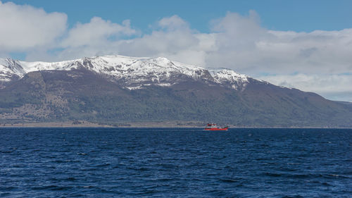 Scenic view of sea by snowcapped mountain against sky