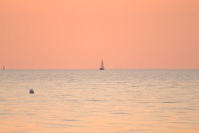 Sailboat sailing on sea against clear sky during sunset