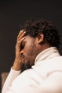 Side view of man with eyes closed against black background
