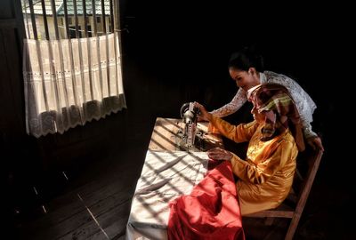 Woman teaching sister using sewing machine