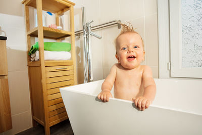 Portrait of cute baby boy sitting in bathroom