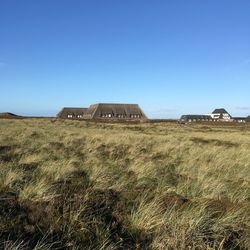 Barn on field against clear blue sky