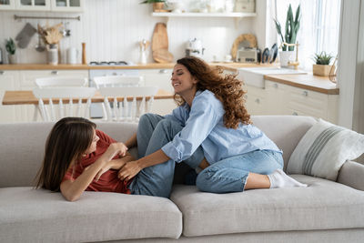 Mother and teen girl daughter enjoying time at home, tickling each other and laughing