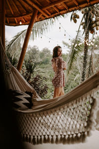 Portrait of young woman standing on hammock