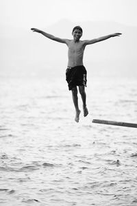 Full length of shirtless man jumping on beach