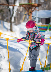 Girl crossing rope bridge during winter