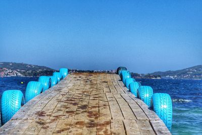 Pier over sea against clear blue sky