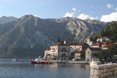 Sailboats in sea by townscape against mountain