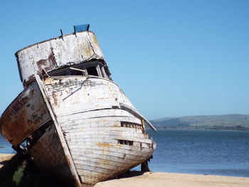 Abandoned boat by sea against clear sky