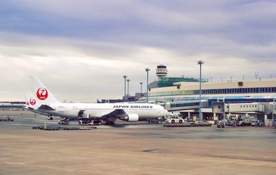 Airplane on airport runway against sky