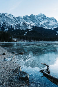 Scenic view of lake by snowcapped mountains against sky