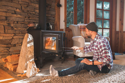 Man sitting on carpet by fireplace at home