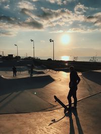 Silhouette man at skatepark against sunset