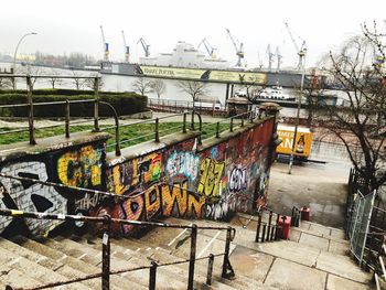 Graffiti on wall by river in city against sky
