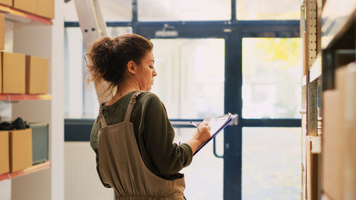 Side view of young woman looking through window