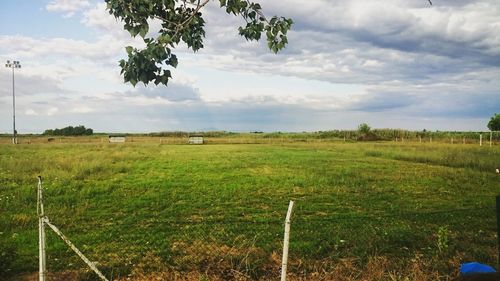 Scenic view of grassy field against cloudy sky