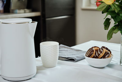 Electric kettle and cup for tea on table